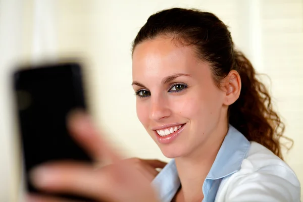 Jovem mulher olhando e sorrindo para o celular — Fotografia de Stock