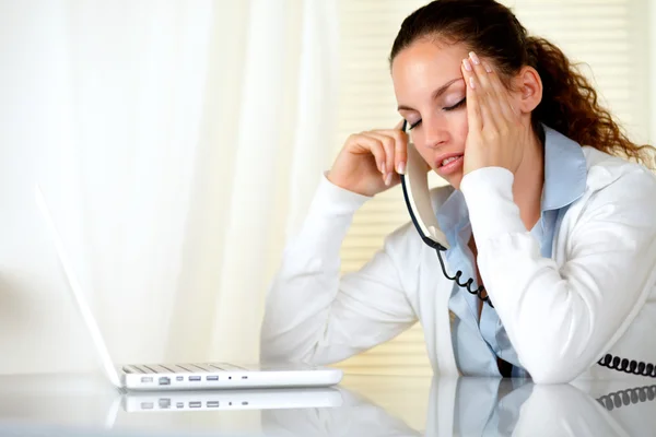 Mulher cansada com dor de cabeça falando ao telefone — Fotografia de Stock