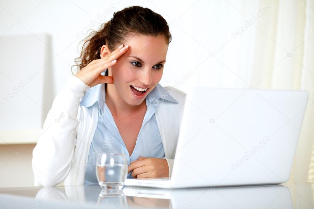 Excited young woman reading on laptop screen