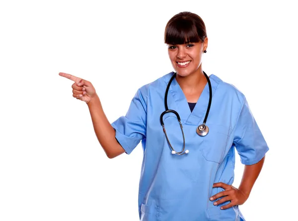 Sonriente joven enfermera mirándote apuntando a la derecha — Foto de Stock