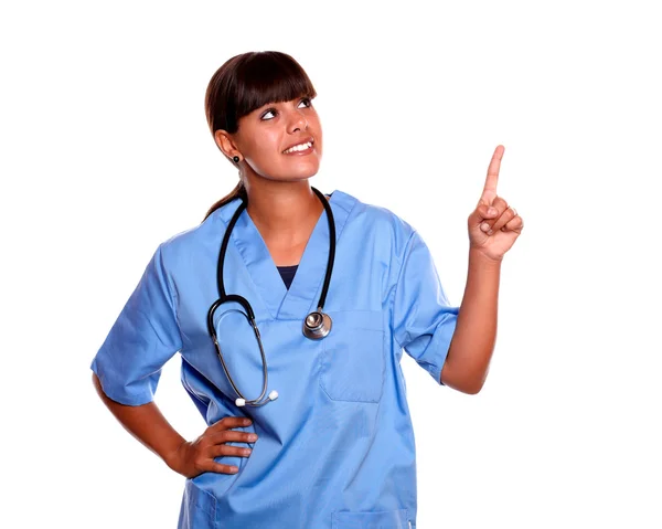 Усміхнена молода медсестра дивиться і вказує вгору — стокове фото