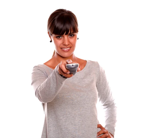 Smiling young woman using a tv remote — Stock Photo, Image