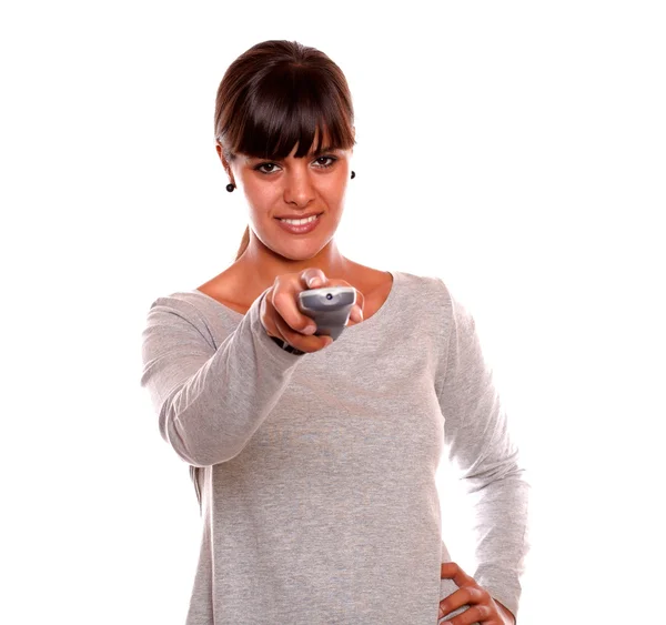 Sorrindo jovem mulher usando um controle remoto de TV — Fotografia de Stock