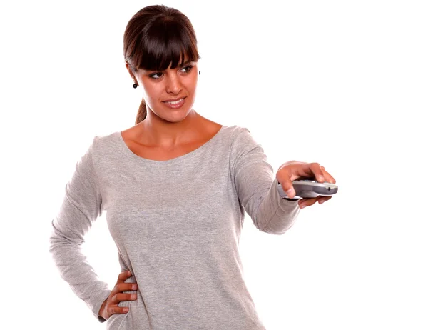 Mujer joven con estilo utilizando un control remoto de televisión — Foto de Stock