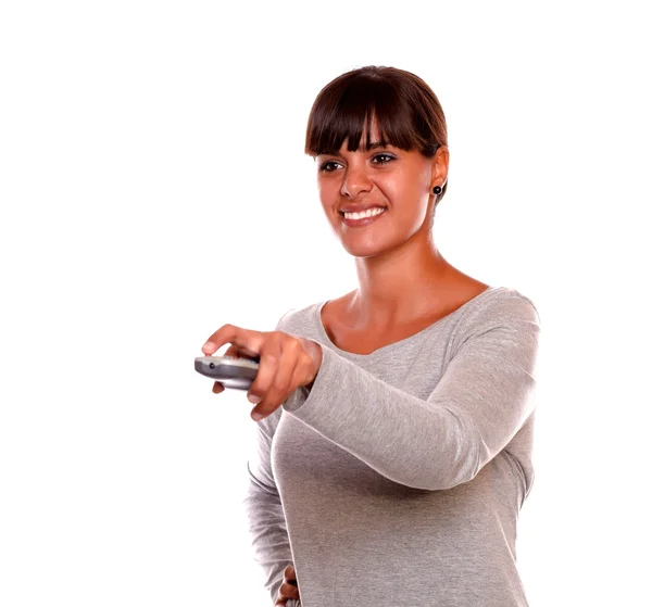 Sorrindo jovem do sexo feminino usando um controle remoto de TV — Fotografia de Stock