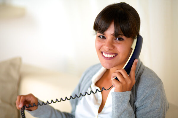 Smiling woman looking at you conversing on phone