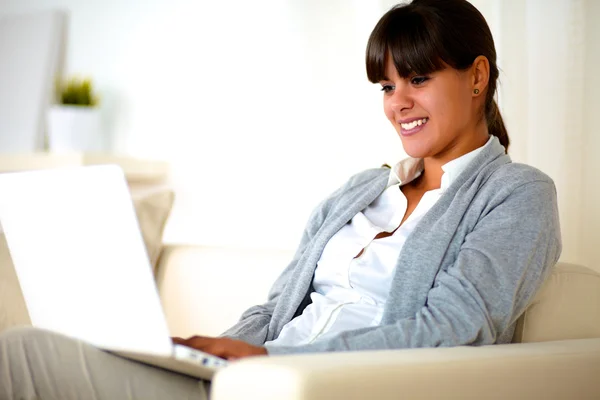 Mujer joven sonriente leyendo la pantalla del ordenador portátil — Foto de Stock