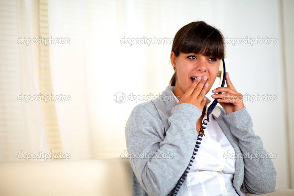 Surprised young woman conversing on phone