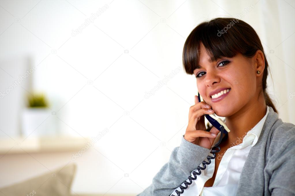 Smiling woman looking at you speaking on phone