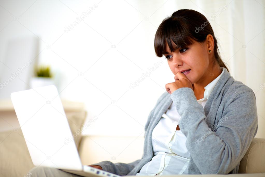 Reflective young woman reading the laptop screen