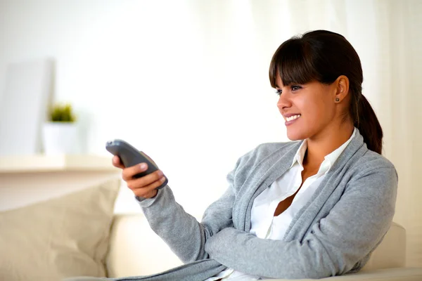 Junge Frau sitzt auf Couch mit Fernbedienung — Stockfoto