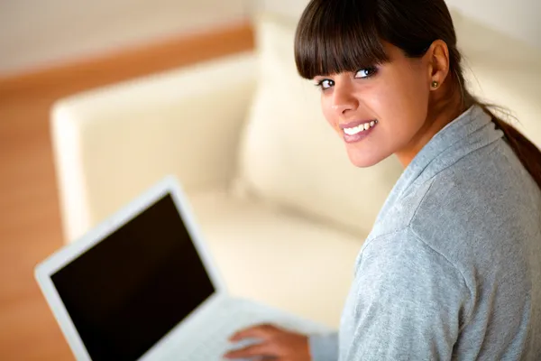 Молодая женщина смотрит на тебя во время работы над ноутбуком — стоковое фото