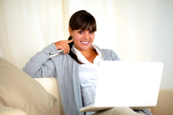 微笑着坐在笔记本电脑前的沙发上的女人 — 图库照片