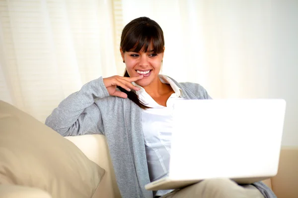 Mulher encantadora sentada no sofá na frente do laptop — Fotografia de Stock