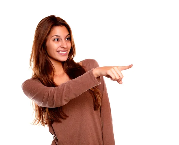 Lachende jonge vrouw aan te wijzen en op zoek links — Stockfoto