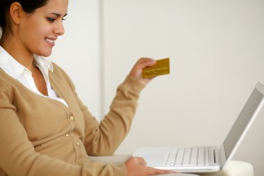 dizüstü bilgisayar ile altın bir kredi kartı tutan genç kadın