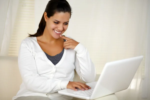 Mujer sonriente sentada en el sofá usando su portátil — Foto de Stock