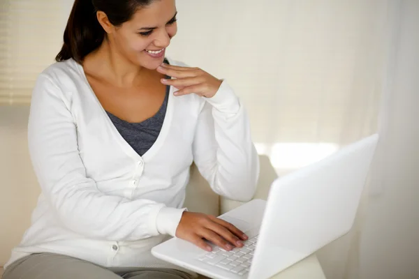 Ung kvinna sitter på soffan med sin bärbara dator — Stockfoto