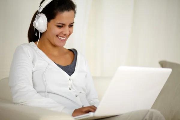 Улыбающаяся молодая женщина с наушниками слушает музыку — стоковое фото