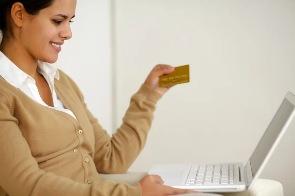 Young woman holding a gold credit card with laptop — Stock Photo, Image