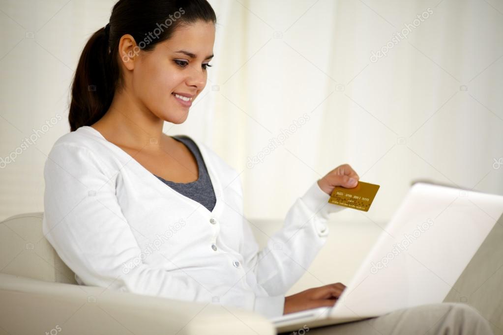 Charming young woman holding a gold credit card