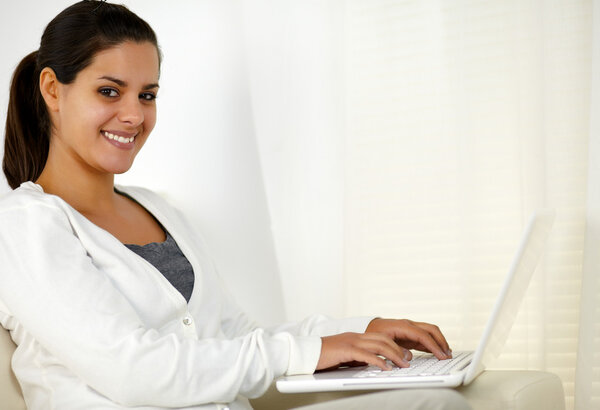 Young woman looking at you working on laptop