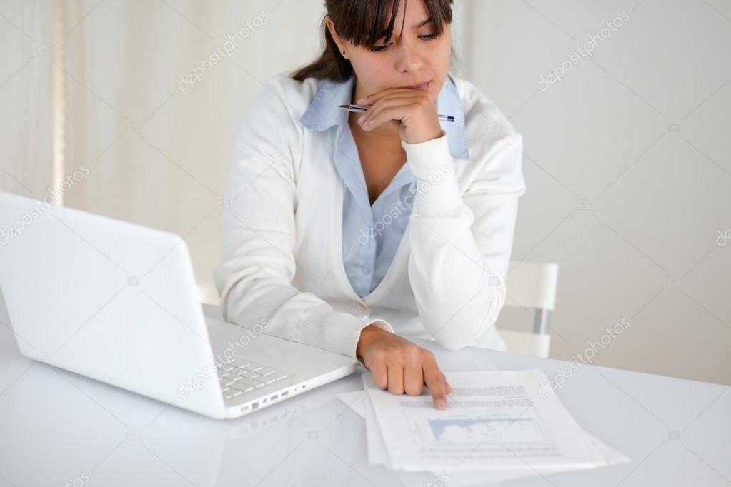 Charming young female studying documents at office