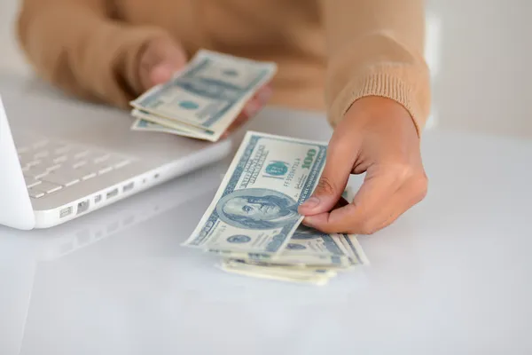Jeune femme comptant des dollars en espèces pour acheter — Photo