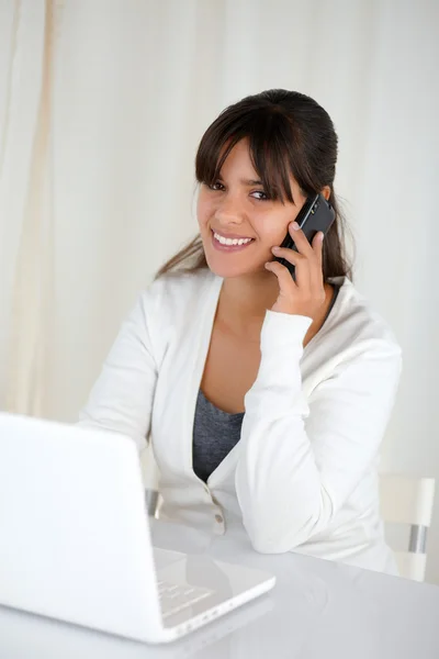 Smiling woman looking at you and using her laptop — Stock Photo, Image