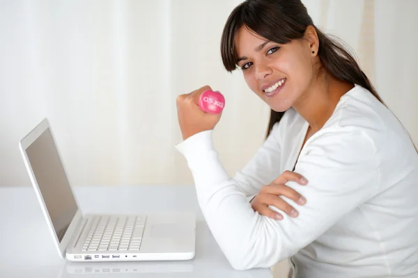 Young woman with weights in front of laptop — Stock Photo, Image