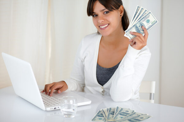 Smiling young woman holding up cash money