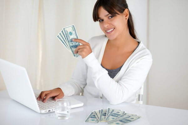 Smiling young female holding up cash money