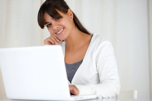 Smiling young woman looking at you using laptop Stock Photo