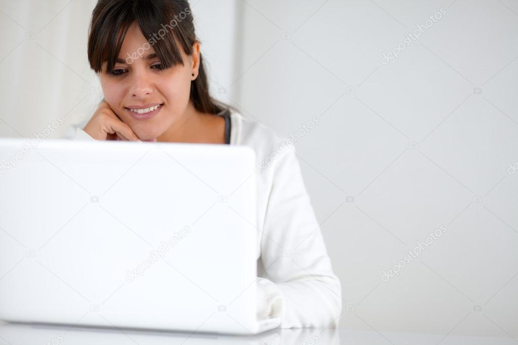 Charming young woman reading on laptop screen
