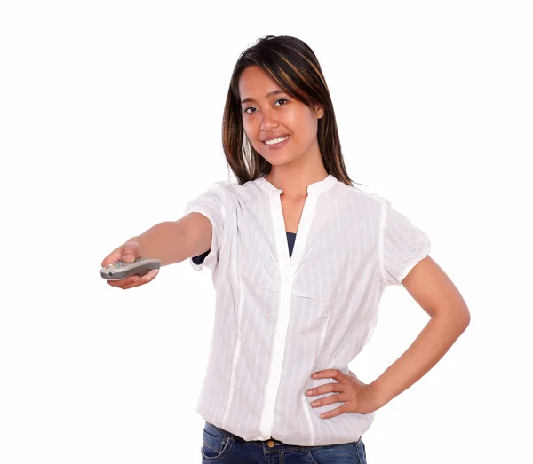 Smiling young woman pointing with remote control — Stock Photo, Image