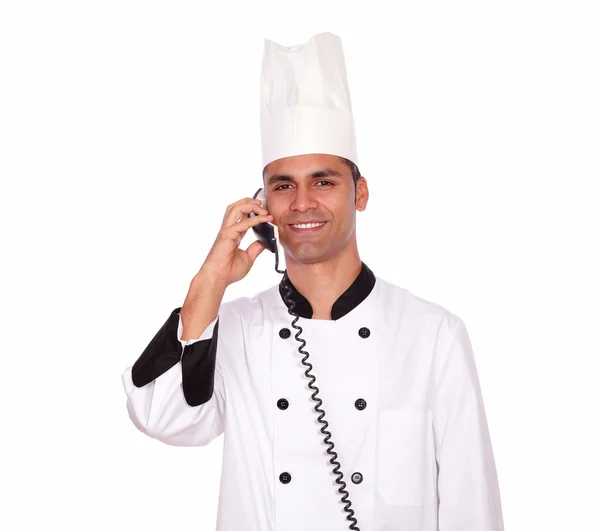 Улыбающийся шеф-повар разговаривает по телефону, стоя — стоковое фото