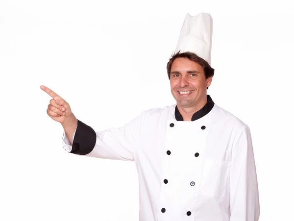 Cozinheiro encantador apontando para sua direita — Fotografia de Stock