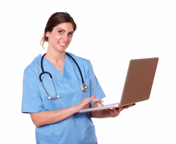Enfermeira sorrindo ao usar seu laptop — Fotografia de Stock