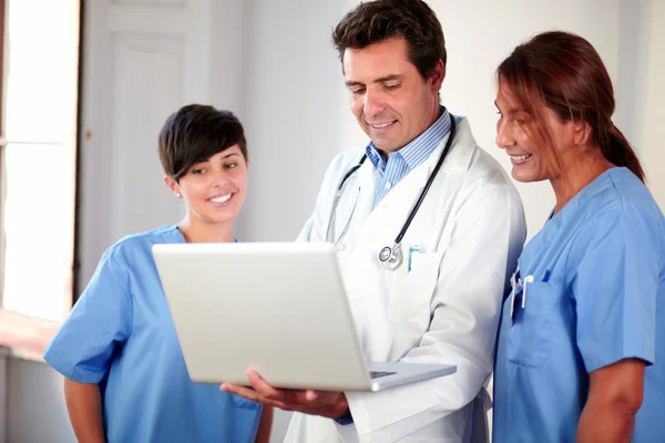 Medicinsk grupp tittar på laptop medan stående — Stockfoto