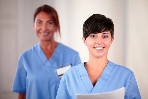 Zwei schöne Krankenschwestern, die dich anschauen und anlächeln — Stockfoto