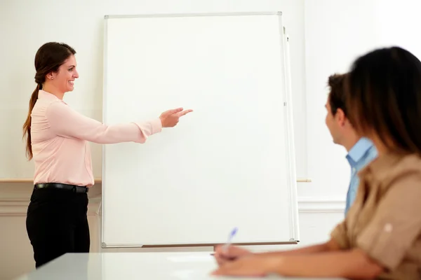 Charming woman standing and pointing at whiteboard — Stock Photo, Image