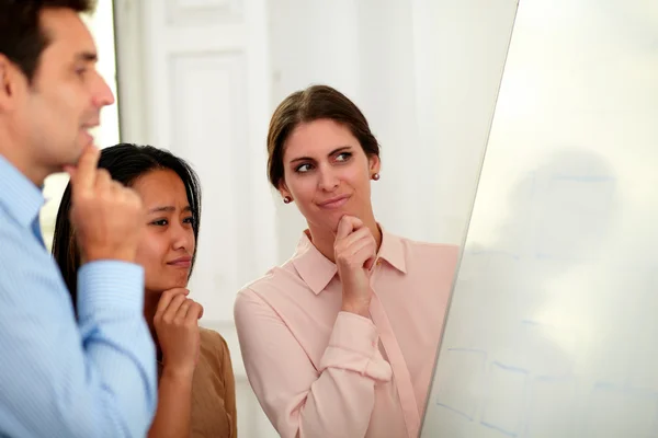 Pensive business team looking on a whiteboard — Stock Photo, Image