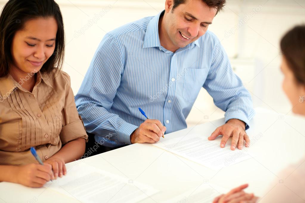 Adult ethnic couple signing a contract