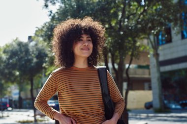 Gün boyunca sırt çantasıyla tek başına yürürken gülümseyen sevimli siyah kız.