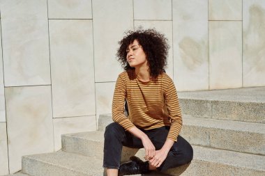 Tatlı siyah kız gün boyunca dışarıda bir çift merdivende tek başına otururken düşünceli görünüyor.