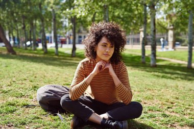 Gün boyunca parkta tek başına otururken çok düşünceli görünen tatlı siyah bir kadın.