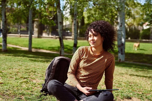 Atraktivní Mladá Černoška Vypadá Zamyšleně Zatímco Sedí Tabletem Ruce Parku — Stock fotografie