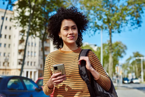 Jovem Mulher Negra Atraente Usando Celular Enquanto Caminha Sozinha Livre — Fotografia de Stock