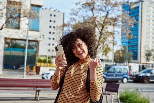 Sırt Çantalı Neşeli Siyahi Kadın Şehirde Cep Telefonu Tutarken Kutlama — Stok fotoğraf