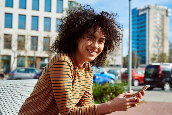 Mulher Negra Jovem Atraente Sorrindo Para Câmera Enquanto Segurava Celular — Fotografia de Stock